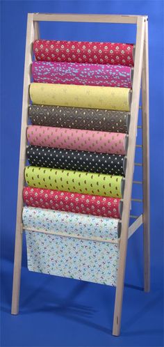 a wooden rack with many different colored fabrics on it's sides and the bottom half is open