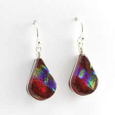 These handmade dichroic glass wide tear shaped earrings that we call lotus are a beautiful rainbow red color that shimmer in the light. Dangle earrings are 1 3/8 inches long and 1/2 inch wide. Earrings come with a pair of clear rubber earring stoppers for the ear wires. To clean: simply polish silver with a jewelry care cloth. Style Number: 17699 Metal: 925 Sterling Silver Dimensions: 1 3/8 inches long and 1/2 inch wide Handmade in North Carolina, USA Rainbow Lotus, Polish Silver, Beautiful Rainbow, Dichroic Glass, Resin Jewelry, Sterling Earrings, Ear Wires, Jewelry Care, Fashion Earrings