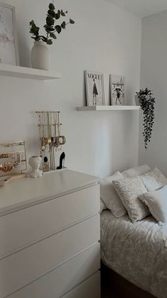 a white bed sitting next to a window in a bedroom under a plant on top of a shelf