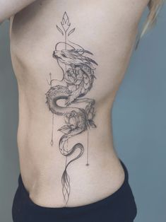 a woman's lower back with a dragon tattoo on her stomach and an arrow in the middle