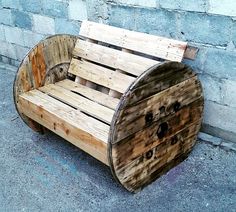 a wooden bench made out of pallets sitting in front of a brick wall