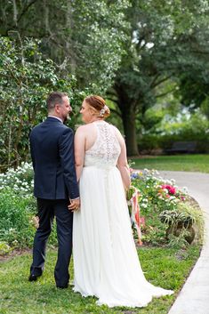 a man and woman standing next to each other in front of some flowers on the grass