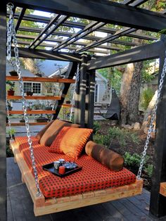 an outdoor swing bed made out of pallet wood and rope with pillows on it