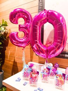 a table topped with pink balloons and decorations