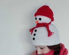 a woman wearing a red and white knitted hat with a snowman on it