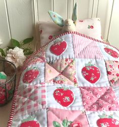 a pink and white quilted bed with strawberrys on it