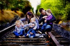 three adults and two children sitting on train tracks