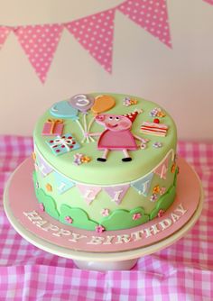 a birthday cake with pep the pig on top is sitting on a pink and white checkered tablecloth