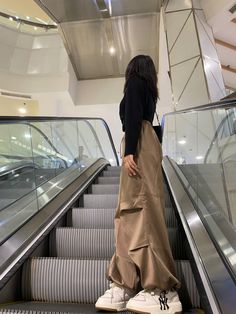 a woman is standing on an escalator with her back to the camera and looking down