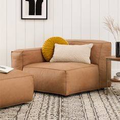 a living room scene with focus on the corner sofa and footstool in the center