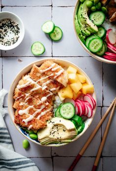 two bowls filled with different types of food next to chopsticks and sauce on the side