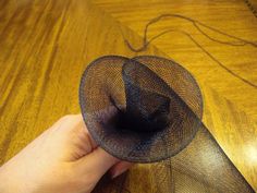 a hand holding a piece of mesh on top of a wooden table