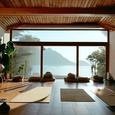 a room with large windows and yoga mats on the floor, overlooking an expansive body of water