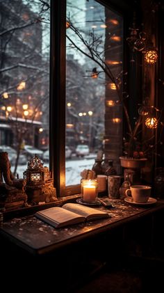 a table with candles, books and other items on it in front of a window