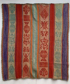 an old rug with multicolored stripes and designs on the bottom, sitting on a white surface