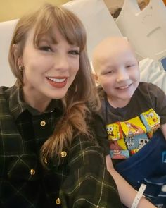 a woman sitting next to a little boy in a hospital bed smiling at the camera