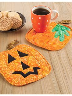 three coasters with pumpkin faces on them, one has a cup of coffee and the other has cookies