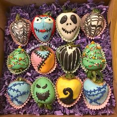 a box filled with halloween cupcakes sitting on top of purple cake wrappers