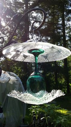 two glass dishes sitting on top of each other in the grass next to some trees