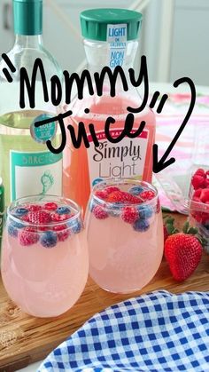 two glasses filled with liquid and strawberries on top of a wooden tray next to bottles