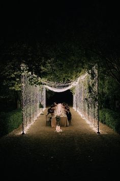 an outdoor dining area with string lights on the walkway and tables set up for dinner