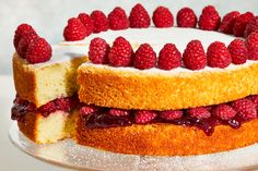 a cake with raspberries on top is cut in half and served on a plate