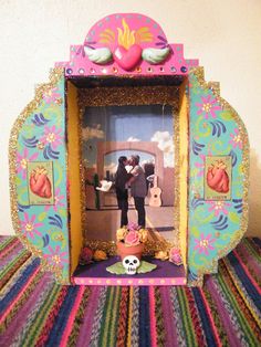 a small photo frame with a couple kissing in front of a heart shaped object on top of a colorful table cloth