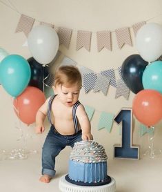 a baby boy standing in front of a birthday cake