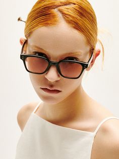 a woman with red hair wearing black glasses