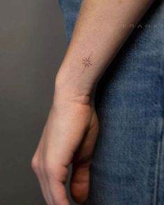 a person's arm with a small star tattoo on the left side of their wrist