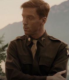 a man in uniform standing with his arms crossed and looking off into the distance,