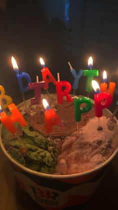 a birthday cake with lit candles sitting in a bucket