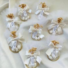 wedding favors in gold and white on a white satin tablecloth with ribbon tied around them