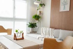 a living room filled with furniture and potted plants on the windows sill next to a window