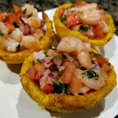 three small food dishes on a plate with shrimp and tomatoes in them, garnished with cilantro