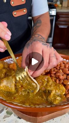 a person is spooning some food out of a bowl with beans on the side