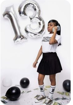 a girl in a skirt is talking on her cell phone while surrounded by balloons and streamers