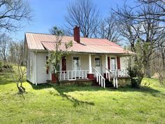 a small white house sitting in the middle of a field