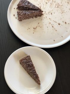 two white plates with pieces of chocolate cake on them, one half eaten and the other half empty