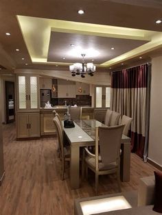 a dining room table and chairs with lights on the ceiling in front of them, along with other furniture