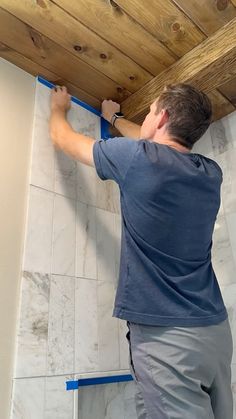 a man is painting the ceiling in his bathroom