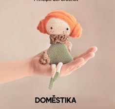 a crocheted doll in the palm of someone's hand with an orange hair