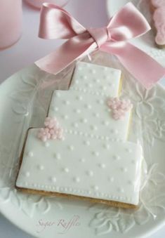 a white plate topped with cookies covered in frosting and pink bow tie decorations on top of it