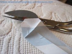 a pair of scissors sitting on top of a white blanket