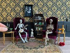 skeleton figurines sitting on chairs in front of a wallpapered living room