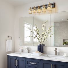 a bathroom vanity with blue cabinets and white counter tops, two large mirrors above the sink