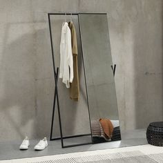 a mirror sitting on top of a floor next to a pile of clothes and shoes