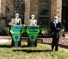 two skeleton statues in front of a house with fake skeletons on the top of them