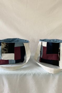 two bags sitting side by side on top of a white tablecloth covered surface,