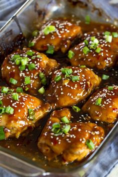 chicken wings with sesame seeds and green onions in a baking dish, ready to be eaten